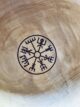 De onderkant van een houten kom van het merk More than Wood, met een Nordic teken van een wegwijzer. Salt + More Than Wood
