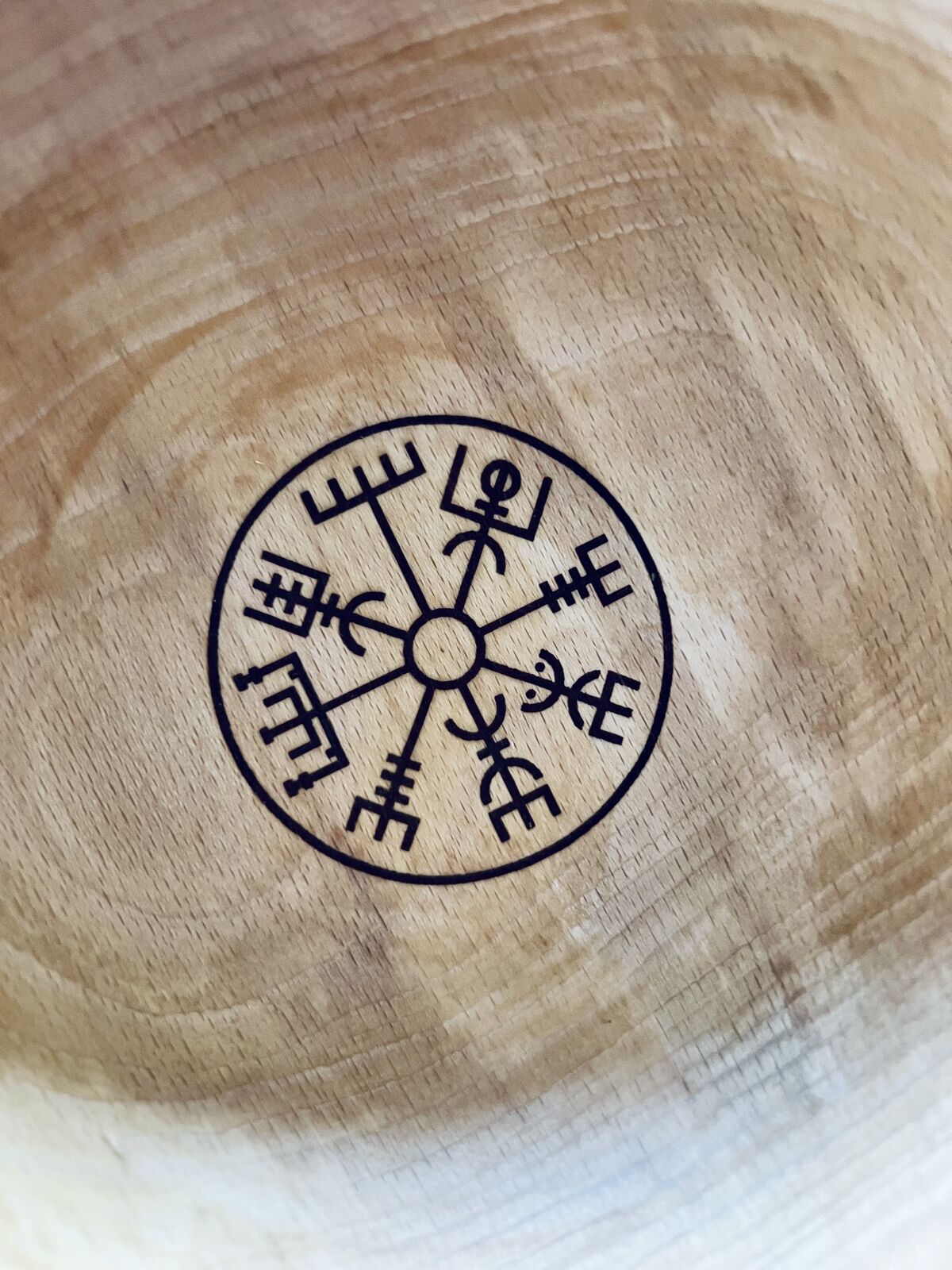 De onderkant van een houten kom van het merk More than Wood, met een Nordic teken van een wegwijzer. Salt + More Than Wood