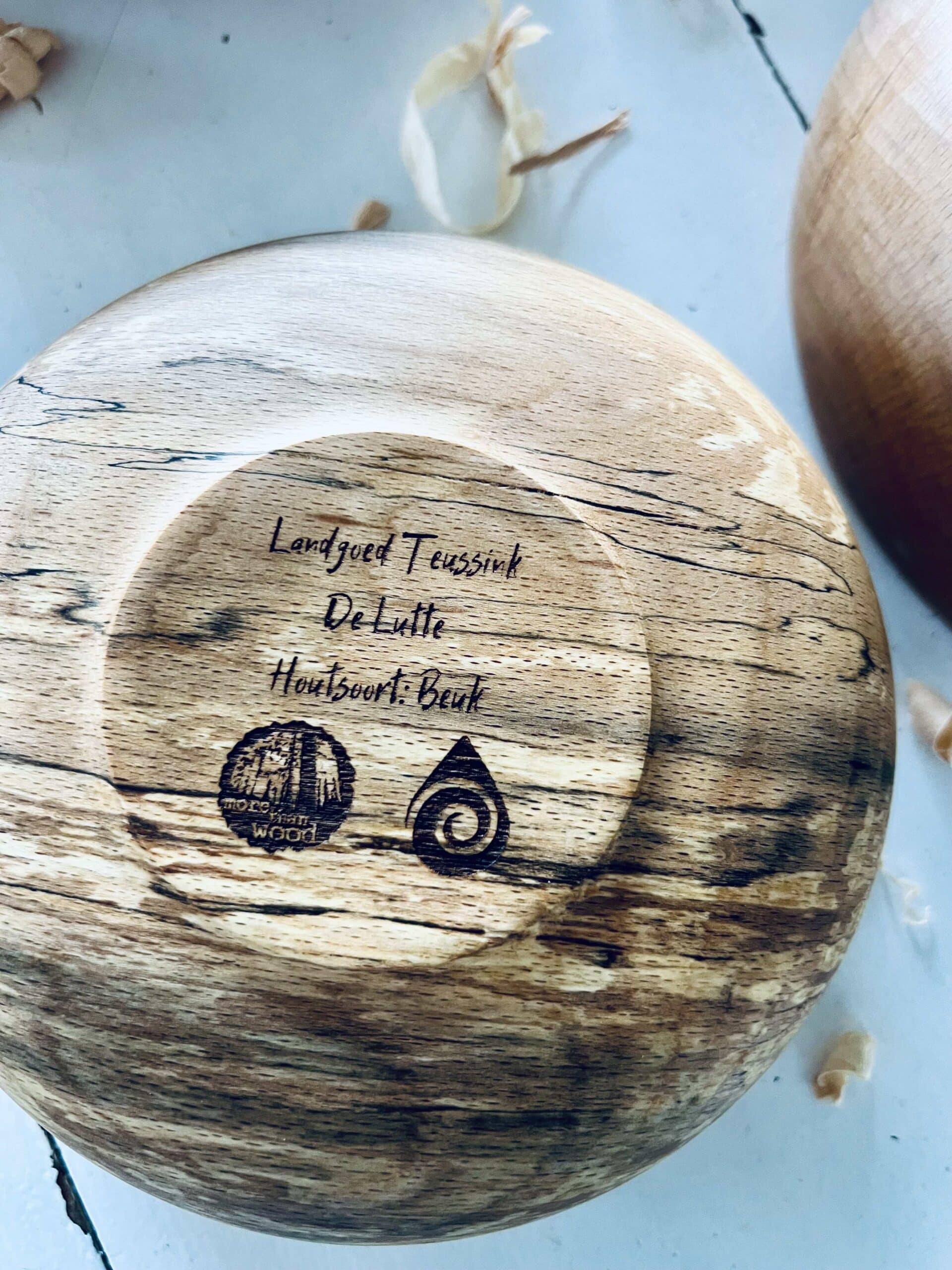 De onderkant van een houten kom van het merk More Than Wood en Salt logo.