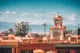 Traditional Moroccan architecture with a minaret and Atlas Mountains rising in the background in Marrakech, Morocco